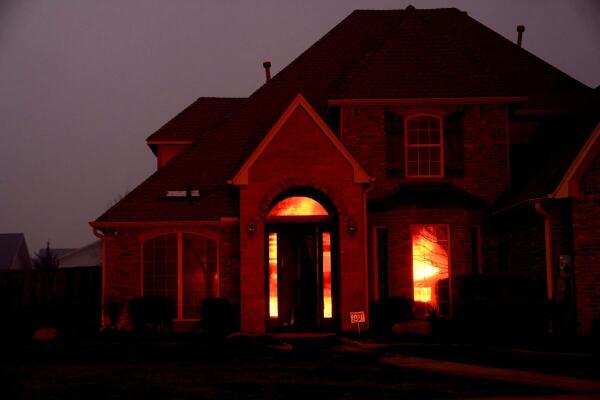 Reflection of a fire burning a residence is seen on glass panes of a residence during a wildfire outbreak in Stillwater.