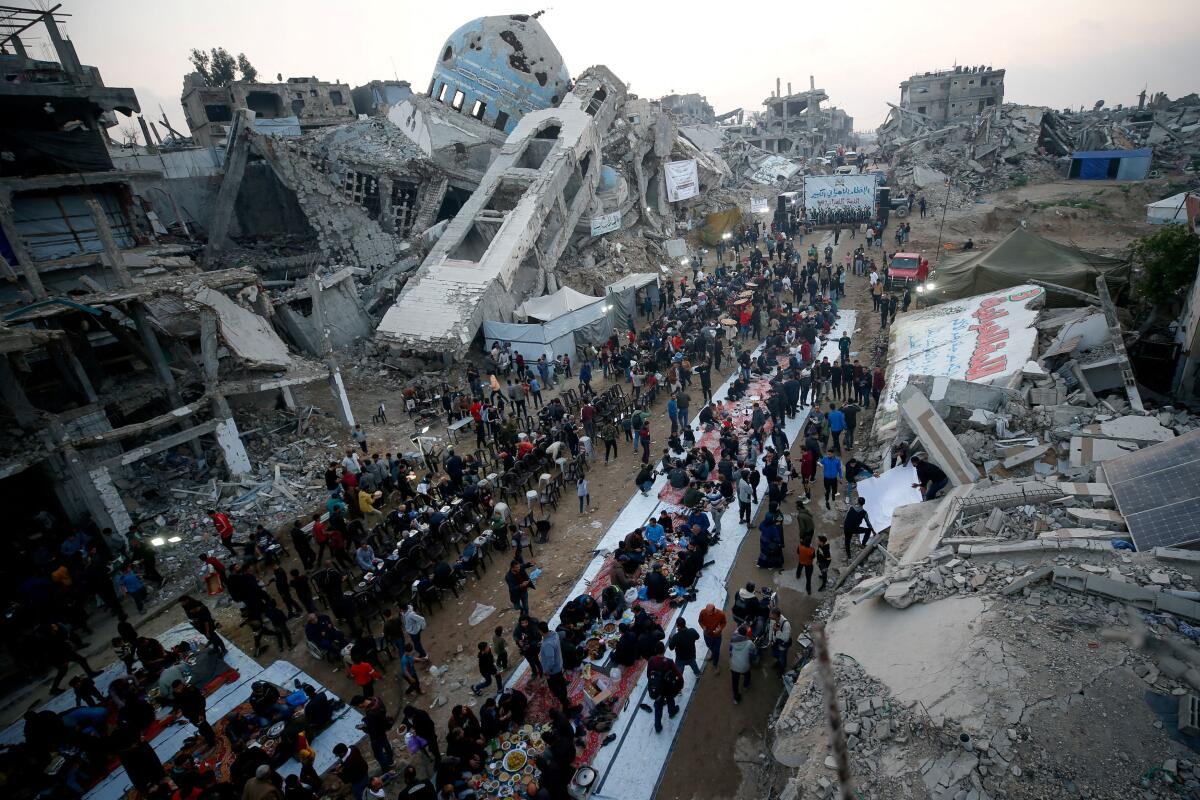 Palestinians gather to break their fast by eating Iftar meals during the holy month of Ramadan, near the rubble of buildings, in the northern Gaza Strip March 15, 2025.