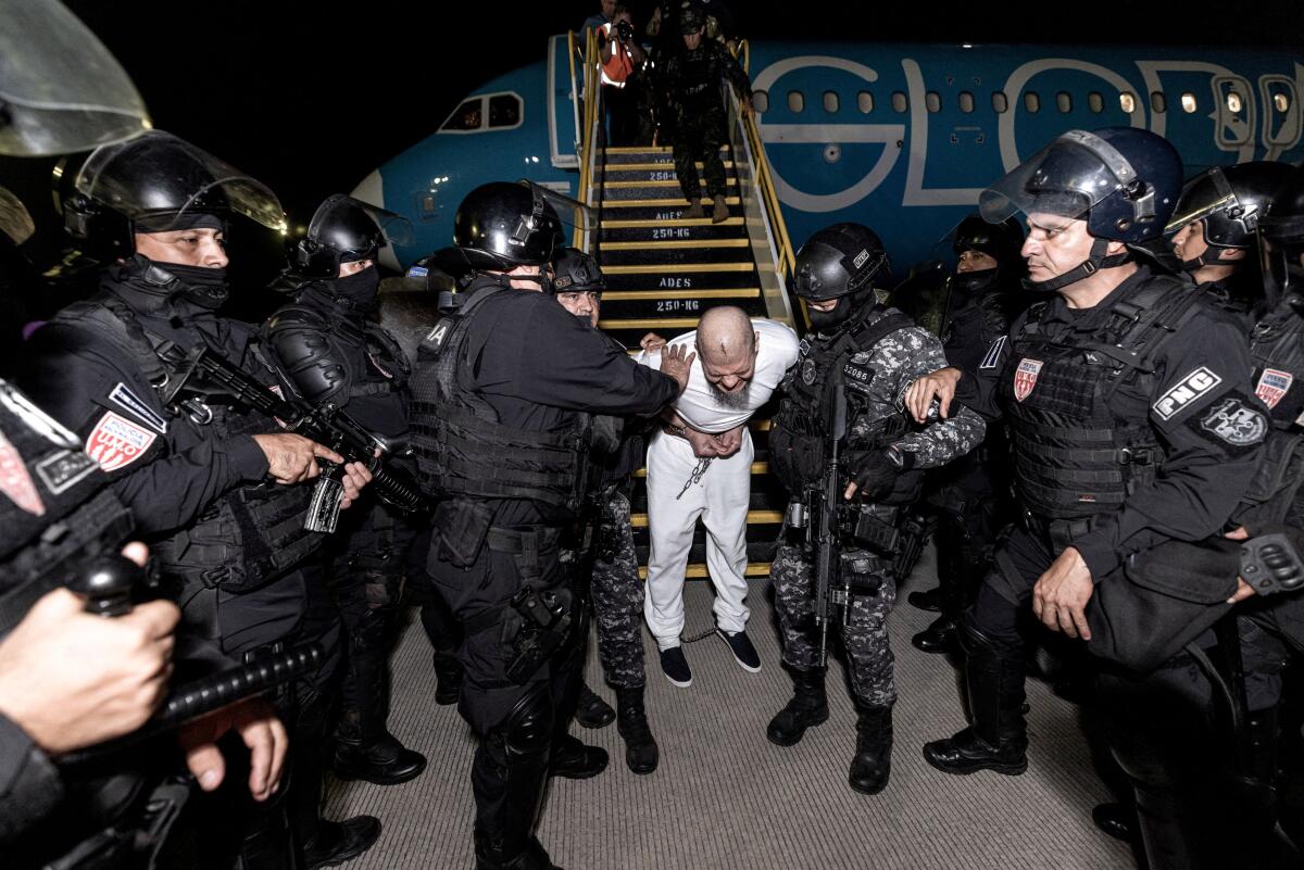 Salvadoran police officers escort alleged members of the Venezuelan gang Tren de Aragua recently deported by the U.S. government to be imprisoned in the Terrorism Confinement Center (CECOT) prison, as part of an agreement with the Salvadoran government, at the El Salvador International Airport in San Luis Talpa, El Salvador, in this handout image obtained March 16, 2025.