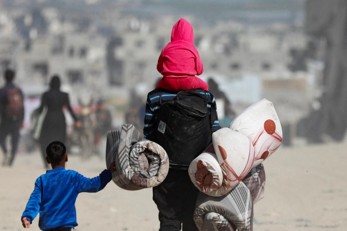 Palestinians make their way to flee their homes, after the Israeli army issued evacuation orders for a number of neighborhoods, following heavy Israeli strikes, in Beit Lahiya in the northern Gaza Strip March 18, 2025.
