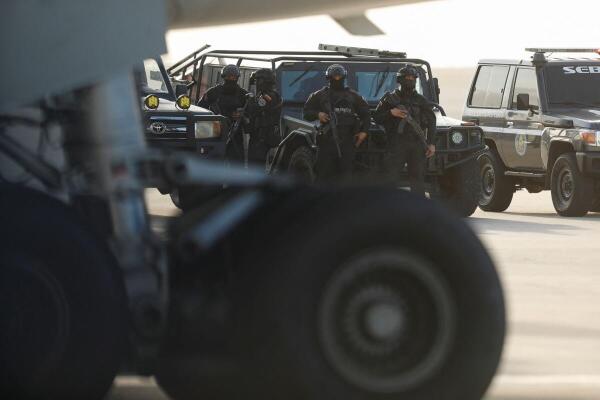 Security personnel stand guard as Venezuelan migrants arrive after being deported from the United States, at Simon Bolivar International Airport, in Maiquetia