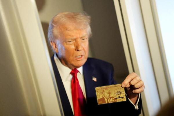 US President Donald Trump holds "The Trump Card" as he speaks with journalists onboard Air Force One en route to Miami, Florida.