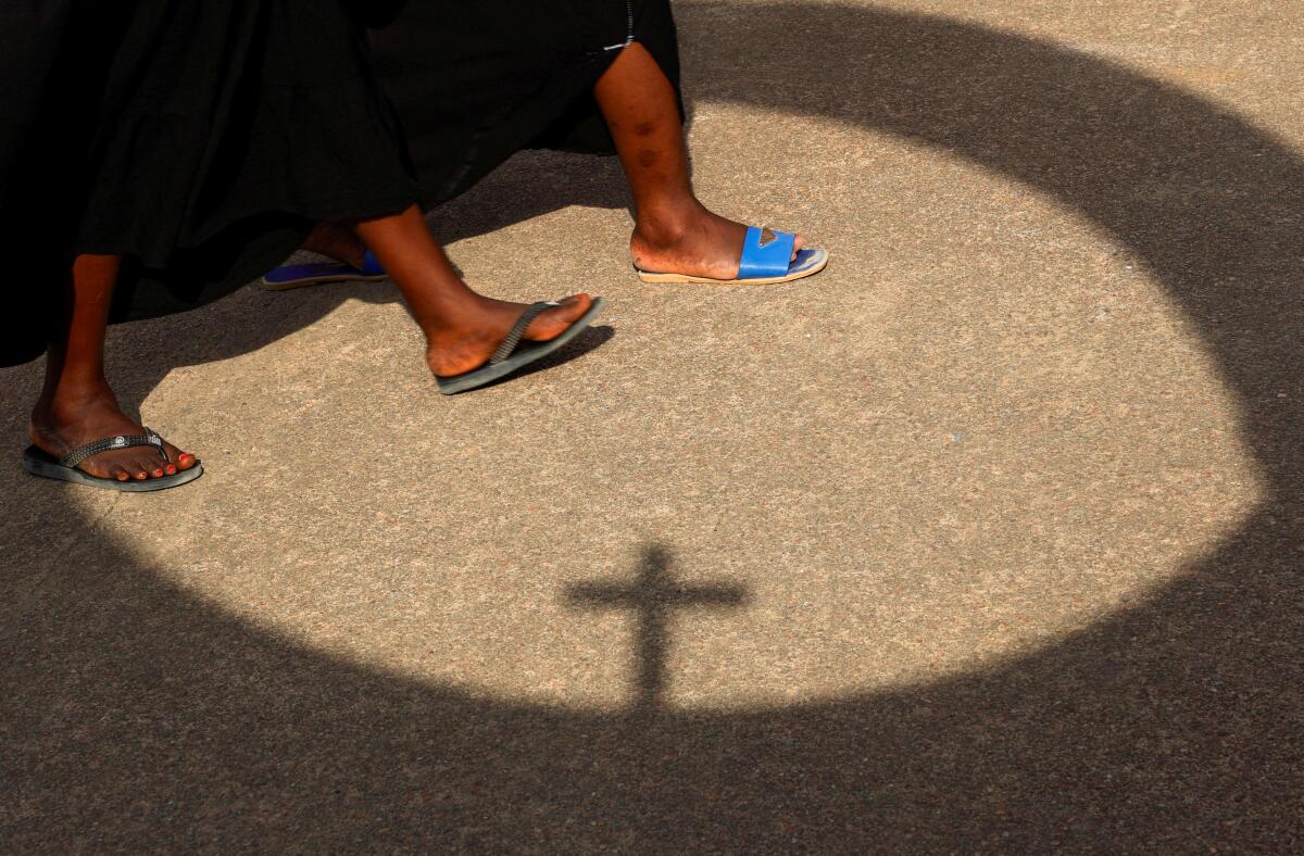 The shadow of a cross is pictured as Catholic faithful arrive to attend a reenactment of the "Via Crucis" (way of the Cross) during Holy Week in Abobote, an area of Abidjan, Ivory Coast