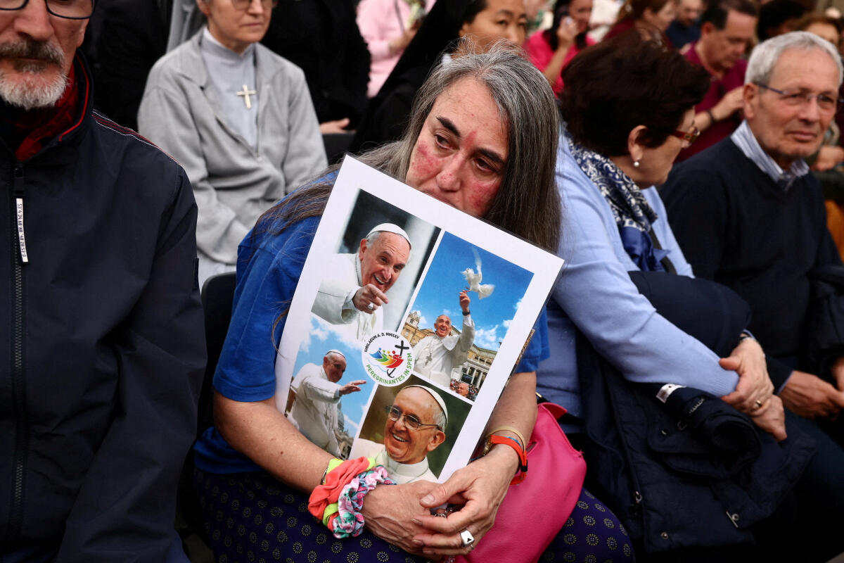 A faithful holds a placard with images of Pope Francis ahead of a rosary, following the death of the pontiff, in St. Peter's square, at the Vatican