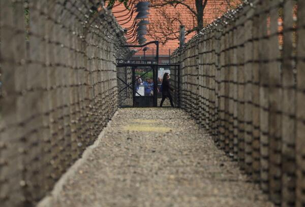 A woman walks near a barbed wire fence before the annual International "March of the Living" through the grounds of the former Auschwitz death camp, to pay tribute to the millions of Jews murdered by the Nazis during World War Two, in Oswiecim, Poland, April 24, 2025. 