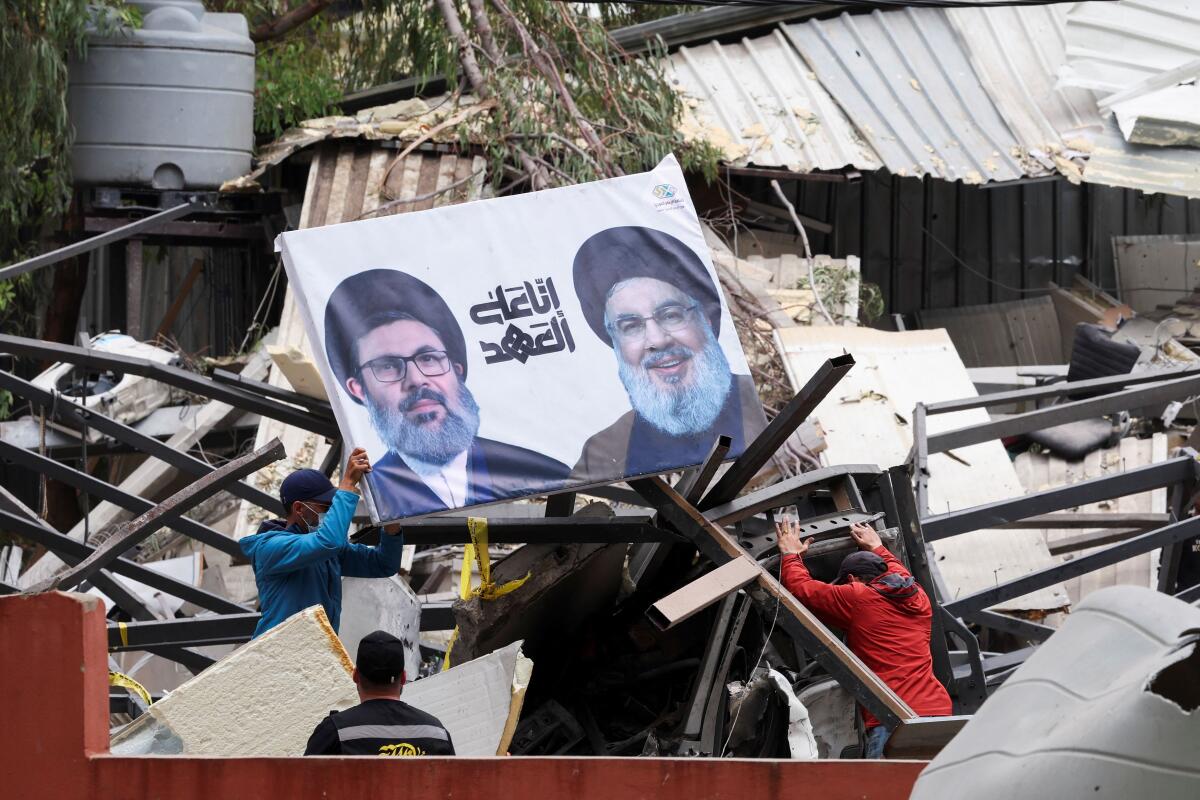 A man carries a picture depicting late Hezbollah leaders Hassan Nasrallah and Hashem Safieddine at the damaged site in the aftermath of Israeli strikes in Beirut southern suburbs, Lebanon, April 28, 2025. 