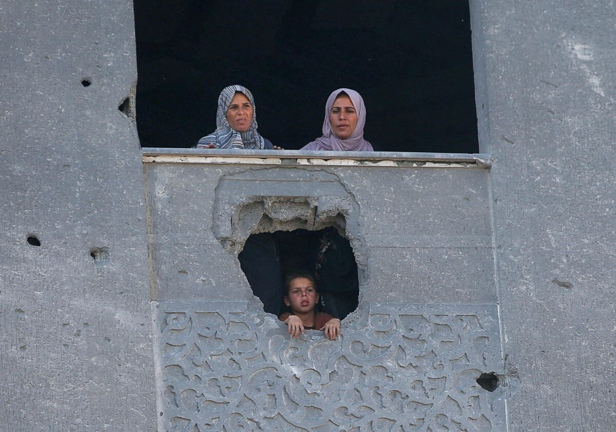 Palestinian women watch, as people search for casualties at the site of an Israeli strike on a house in Jabalia, in the northern Gaza Strip May 2, 2025.