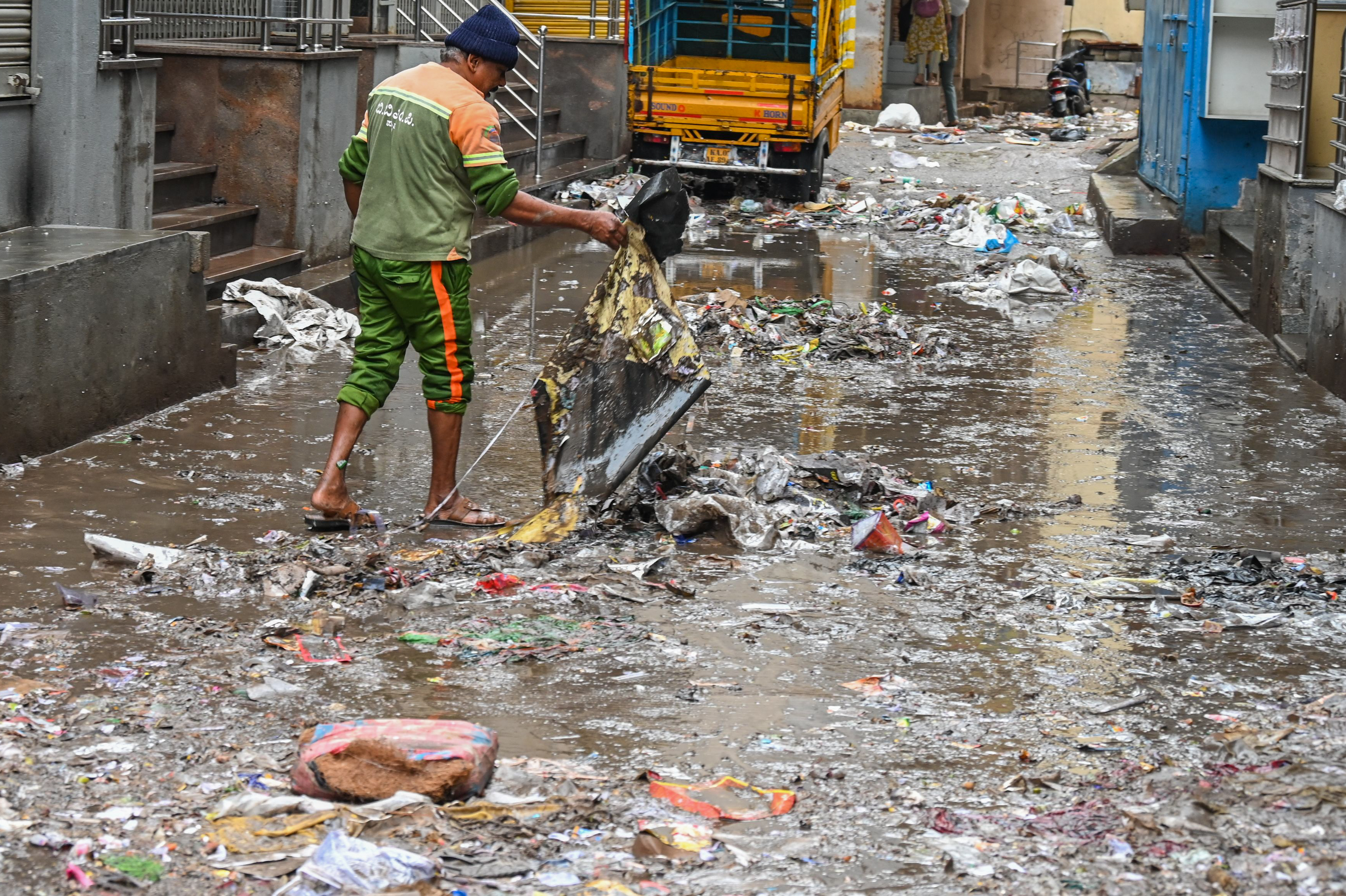 A BBMP pourakarmika cleaning a road in the morning after a heavy rain. 