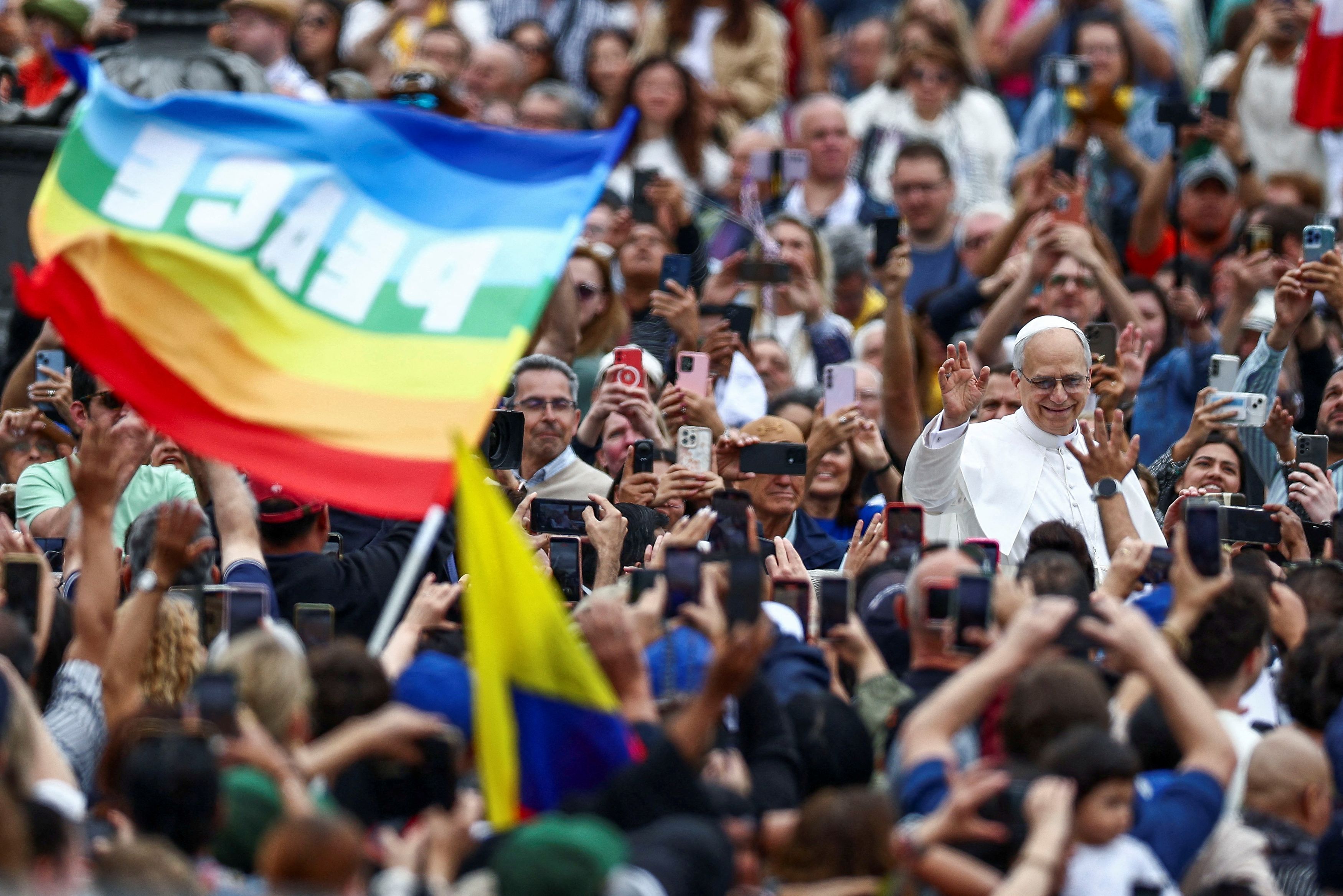A person holds a flag that reads "Peace" as Pope Leo XIV arrives for his first general audience in St. Peter's Square, at the Vatican, May 21, 2025. 