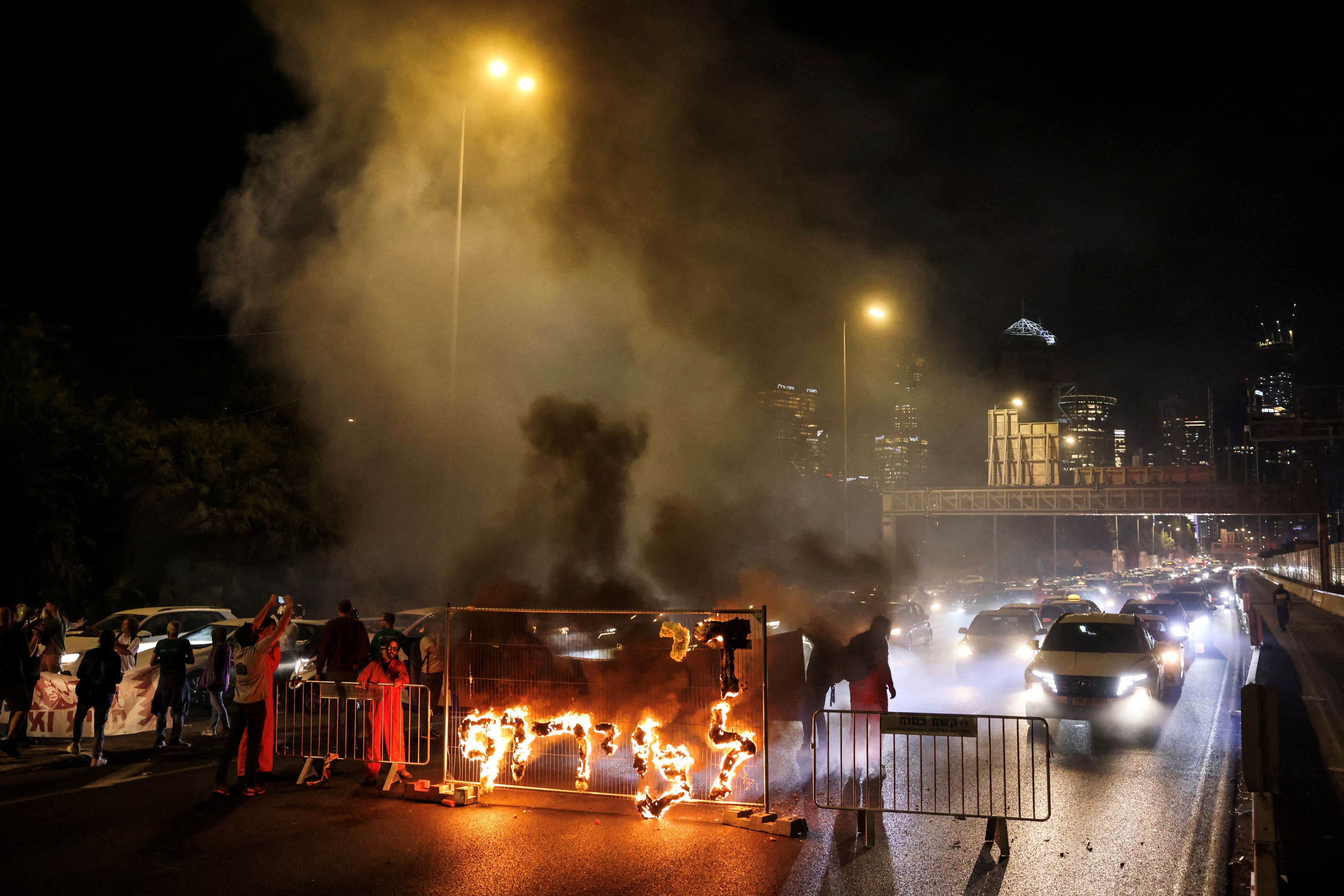 Fire blazes with the words in Hebrew, "Enough with the madness", as demonstrators and relatives of hostages block a road demanding the immediate release of hostages who were kidnapped during the deadly October 7, 2023 Hamas attack, in Tel Aviv Israel May 21, 2025 