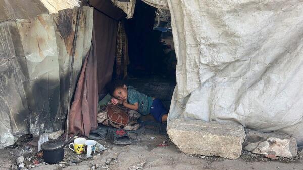A Palestinian child lies inside the tent he took shelter in with his family after being displaced, in Gaza City.