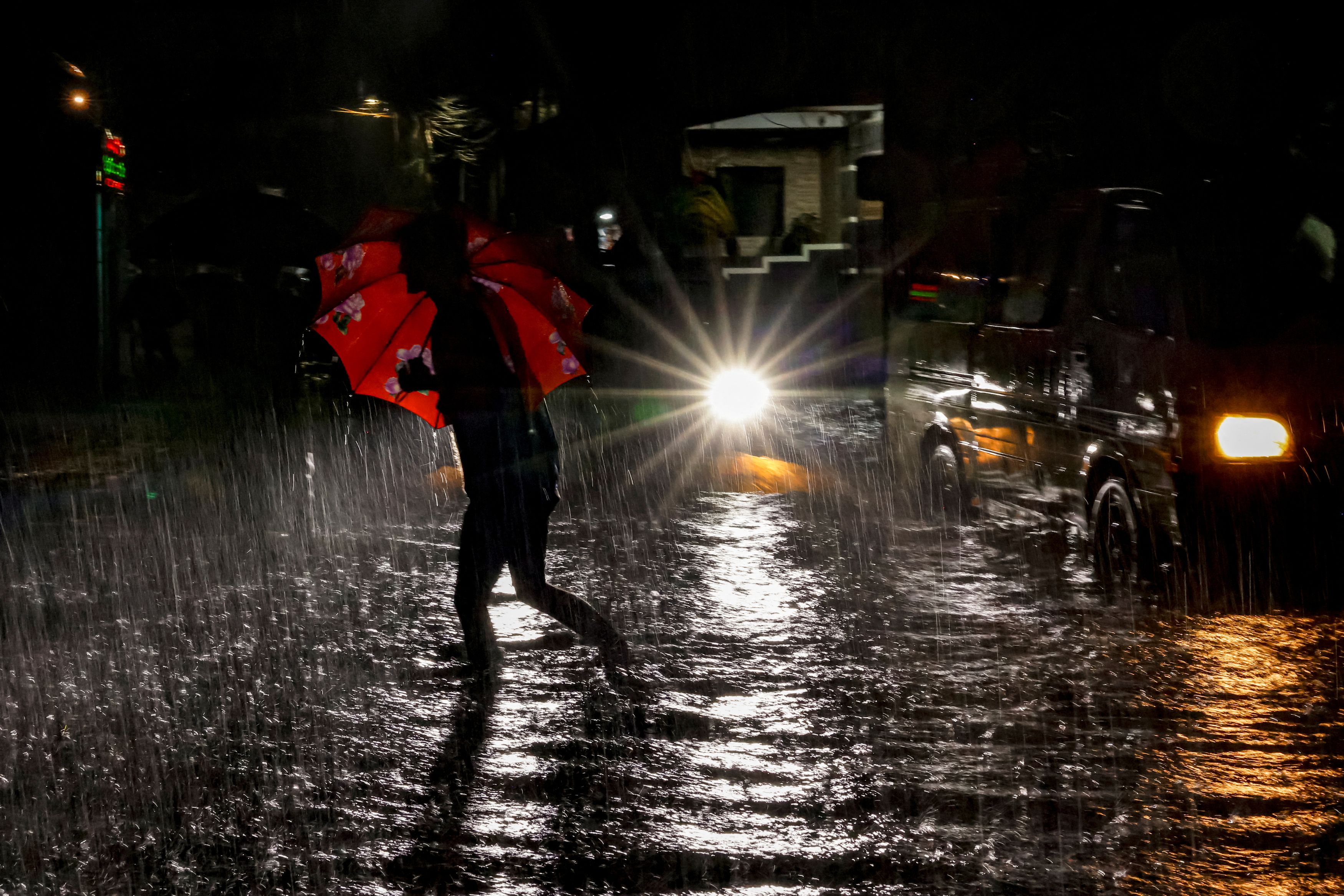 A man with umbrella wades through a water-logged street as it rains, following a depression in the Bay of Bengal, in Dhaka