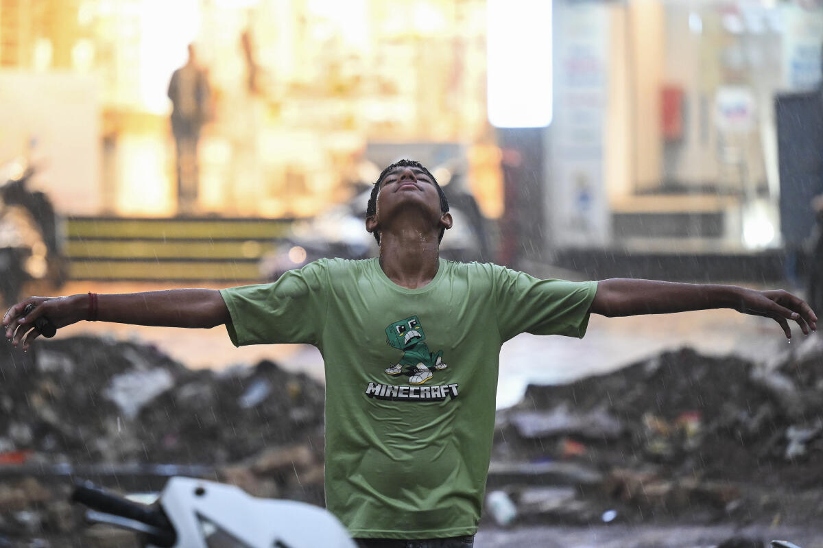 A boy enjoys himself as rain brings respite from the scorching heat, in Bikaner, Rajasthan