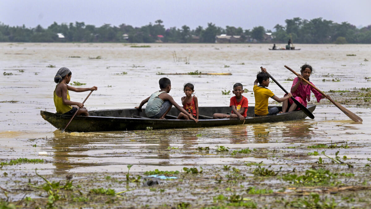 People use a boat to move to safer areas after heavy rainfall triggered floods in Nagaon district of Assam