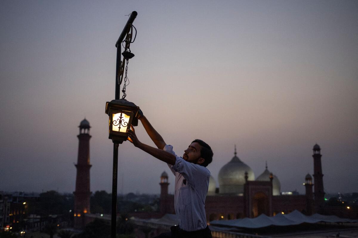 Badshahi Mosque is visible in the background, as Mudassar, 18, cleans lamps at the Haveli Restaurant one day before the Eid ul-Adha celebrations in Lahore, Pakistan