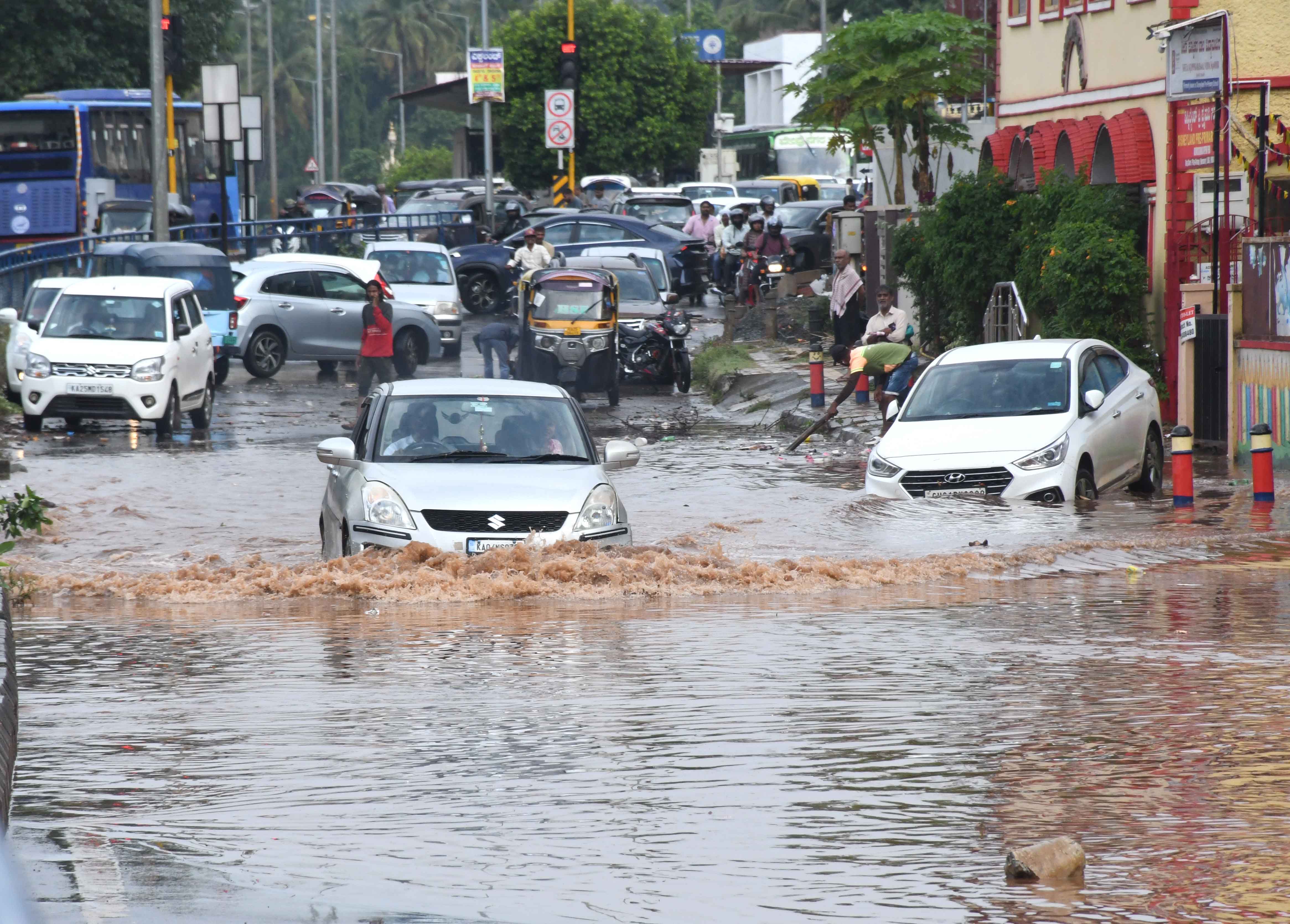 Motorists having a torrid time on a flooded road in front of NTTF in Dharwad. The city experienced a sharp spell of rain in the afternoon. DH PHOTOS