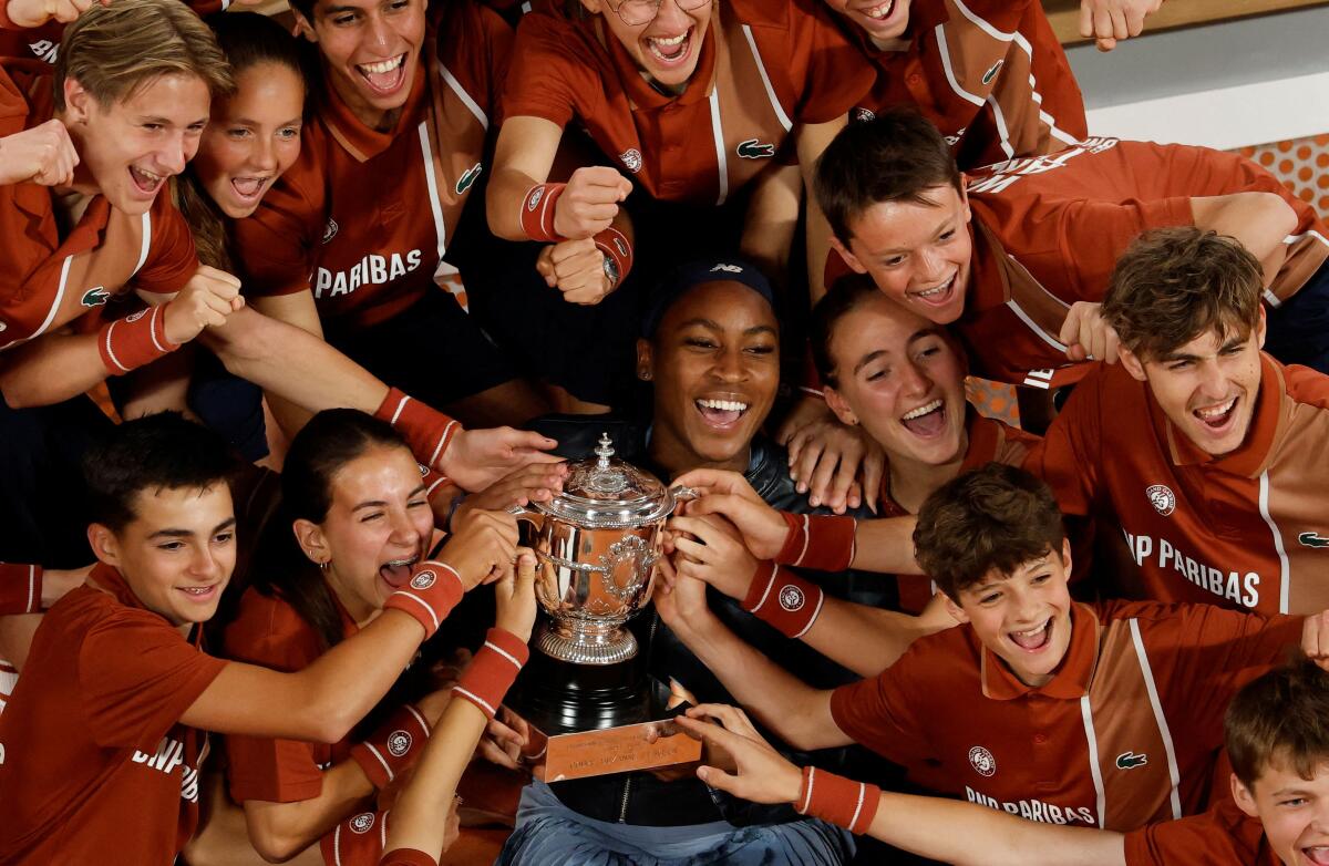 Coco Gauff of the U.S. celebrates with the trophy and the ball kids after winning the women's singles final against Belarus' Aryna Sabalenka.