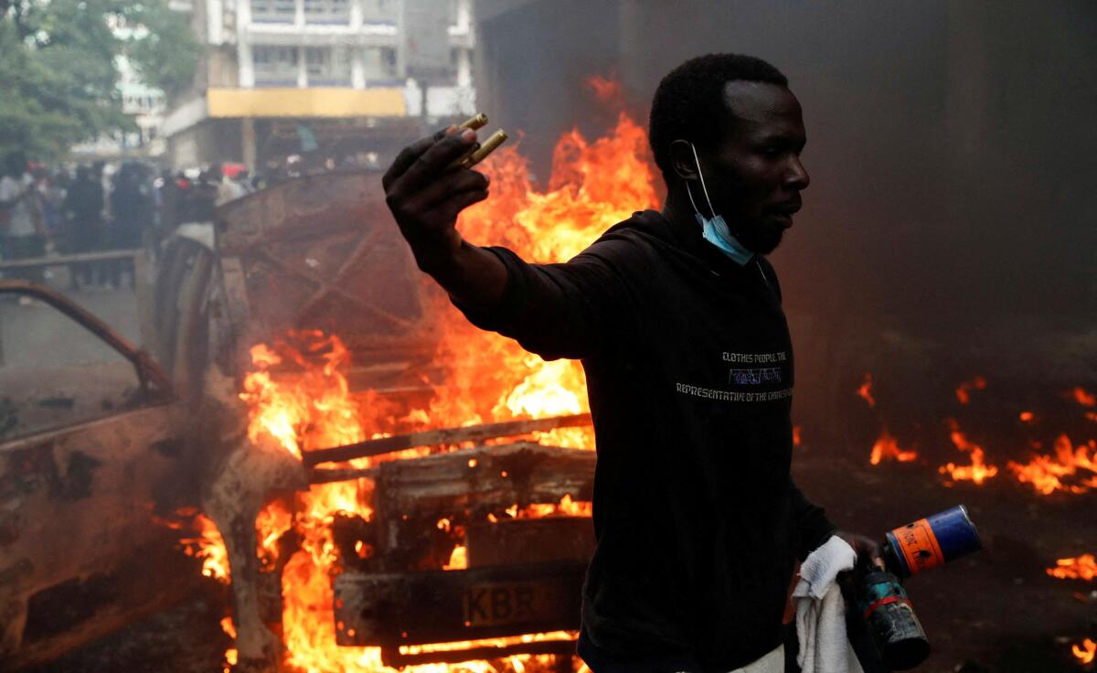 A protestor holds empty bullet shells and teargas canisters as he reacts in front of burning vehicles during a demonstration against the death of a blogger in police custody last week, in downtown Nairobi, Kenya June 12, 2025. 
