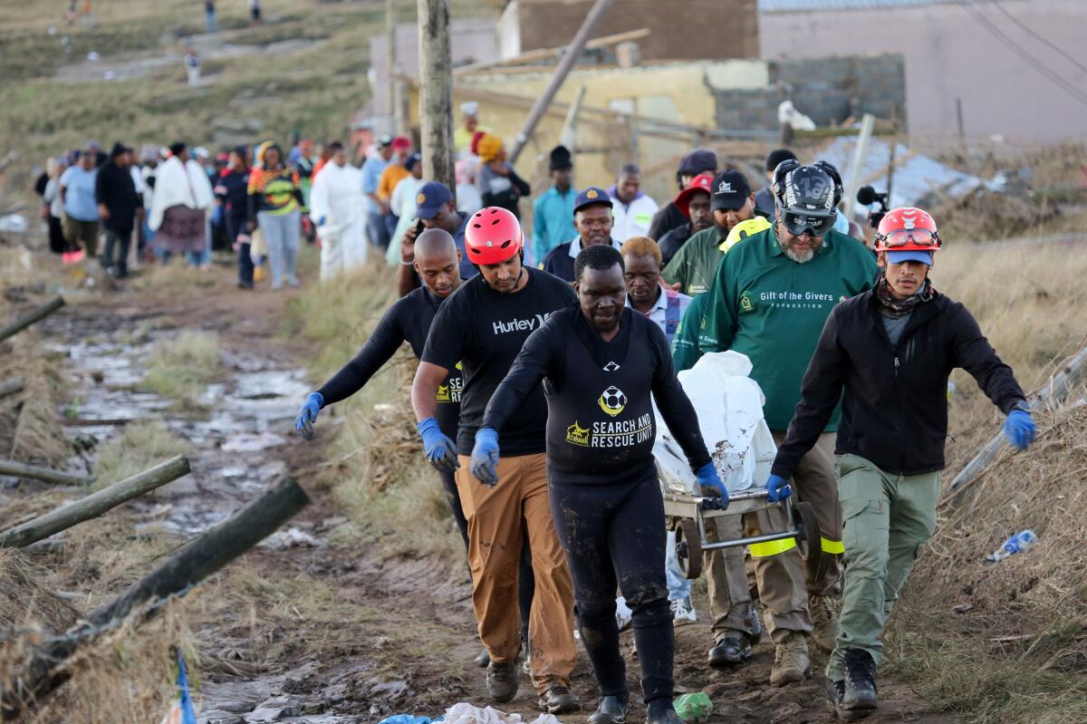 Rescue workers carry the covered body of a victim as the death toll from floods continues to rise, in Mthatha, Eastern Cape province, South Africa, June 12, 2025.