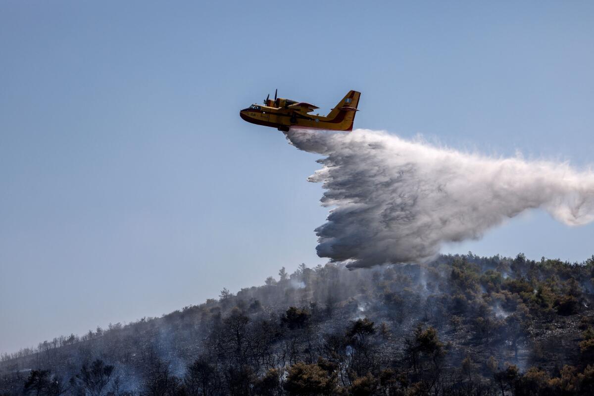 A firefighting plane makes a water drop as a wildfire burns in Ano Souli, near Athens, Greece, June 16, 2025