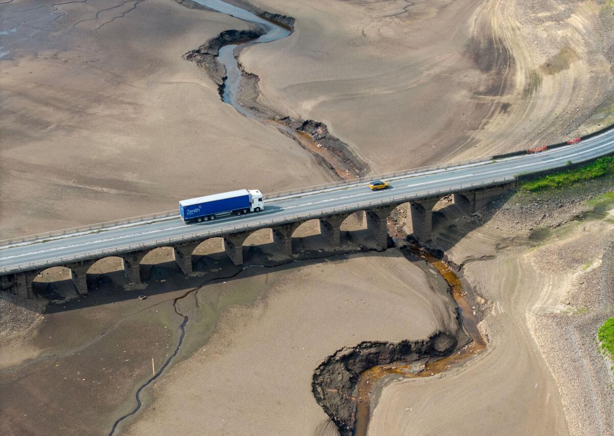 A drone view shows vehicles using a bridge to pass over a dry section of the Woodhead Reservoir after a prolonged period without rain saw water levels drop near Tintwistle, Britain, June 16, 2025.