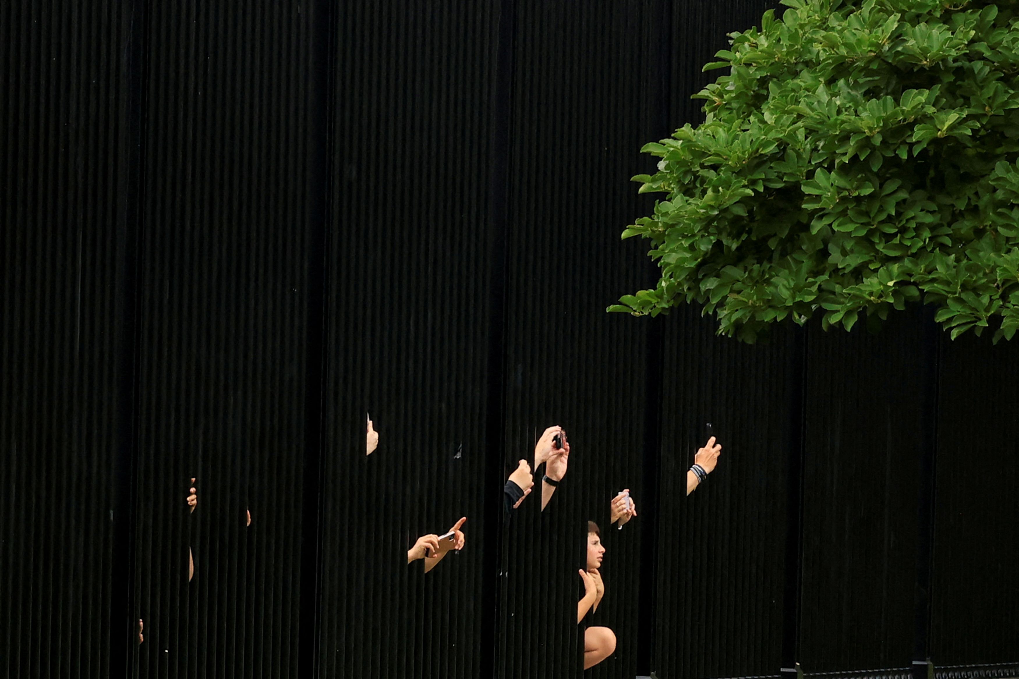 Tourists reach through fencing with their phones to photograph the White House after U.S. President Donald Trump cut his G7 trip short and returned as the Israel-Iran air war raged for a sixth day, in Washington, D.C., U.S., June 17, 2025.