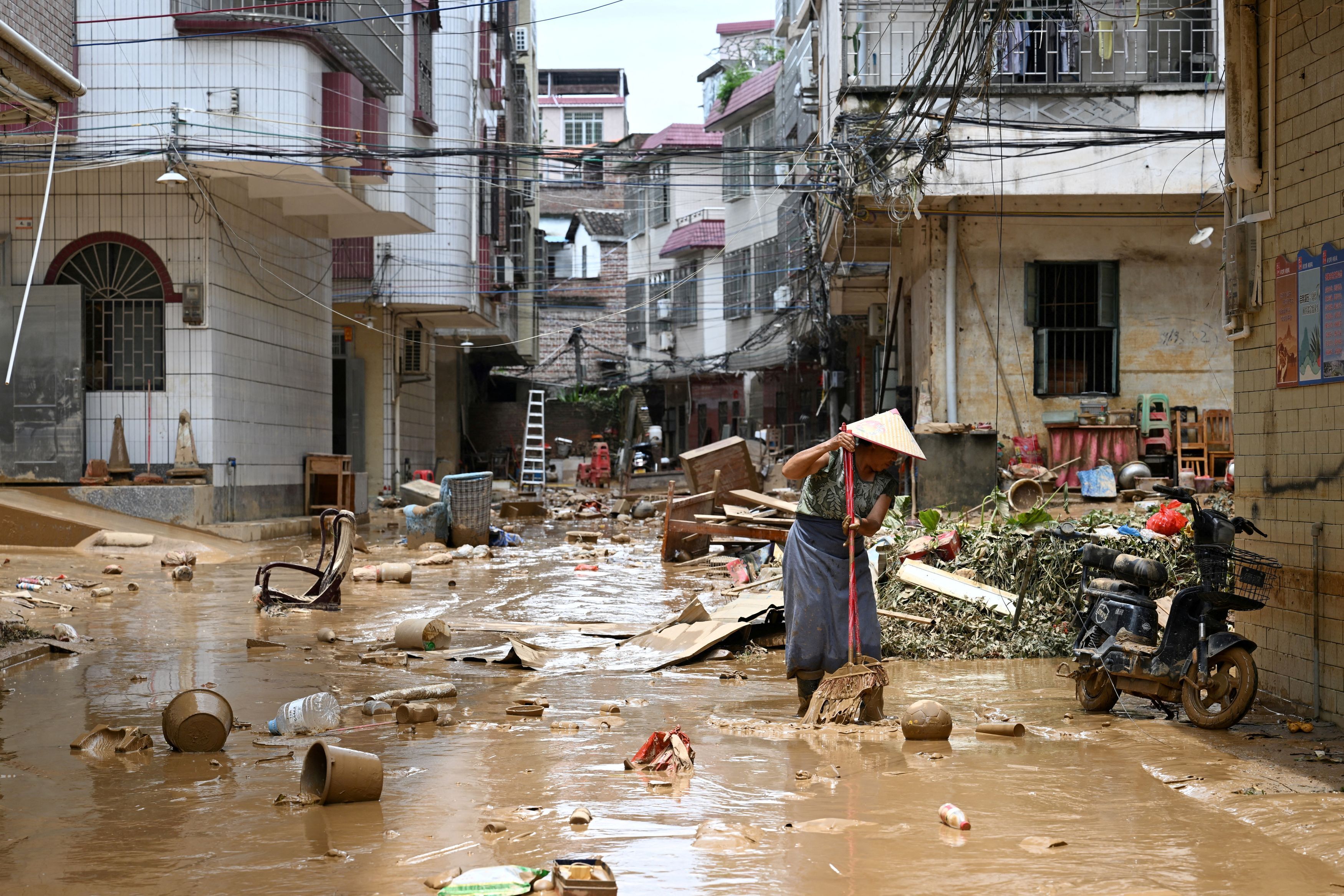 A resident cleans up a street after heavy rainfall led to flooding, in Huaiji county of Zhaoqing, Guangdong province, China June 19, 2025.