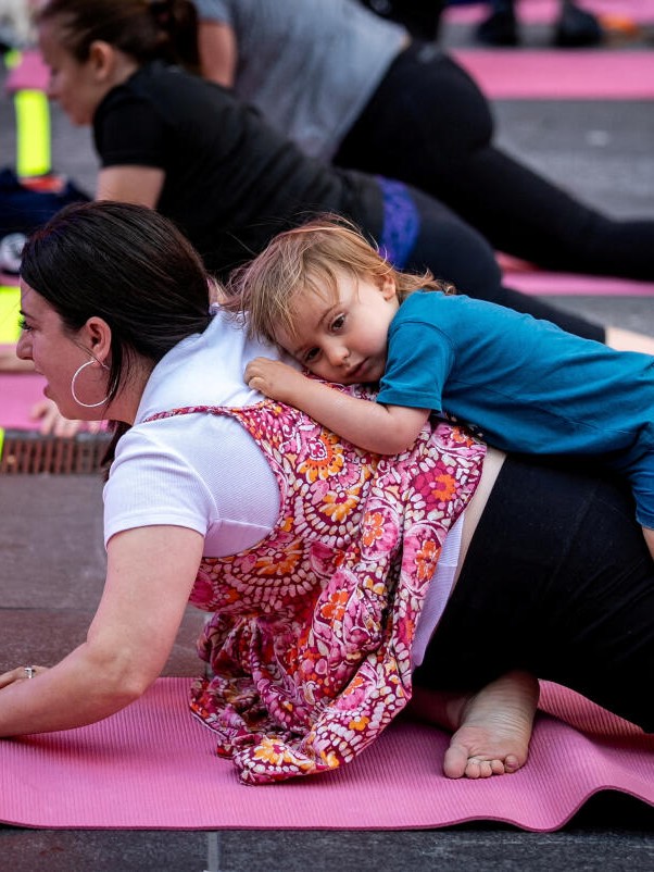 A child lies atop his mother as she takes part in the International Yoga day at Times Square.