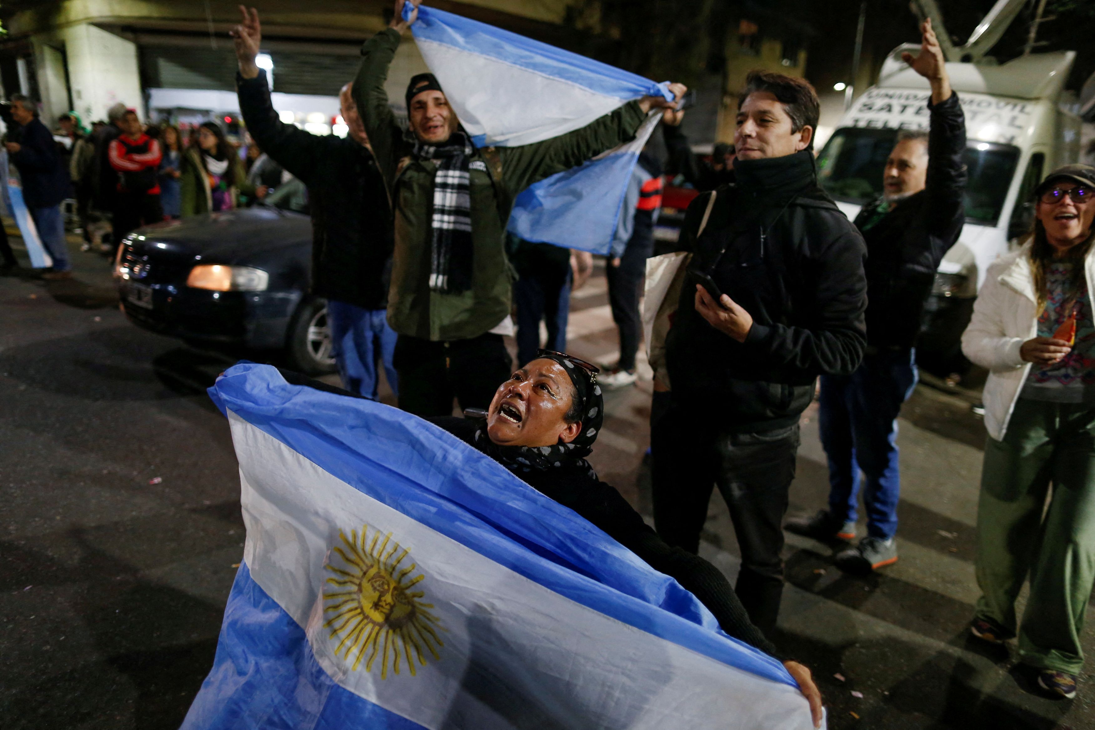 Supporters of Cristina Fernandez de Kirchner hold Argentinian flags outside her home, where the former Argentinian president is serving house arrest, in Buenos Aires, Argentina, June 20, 2025.