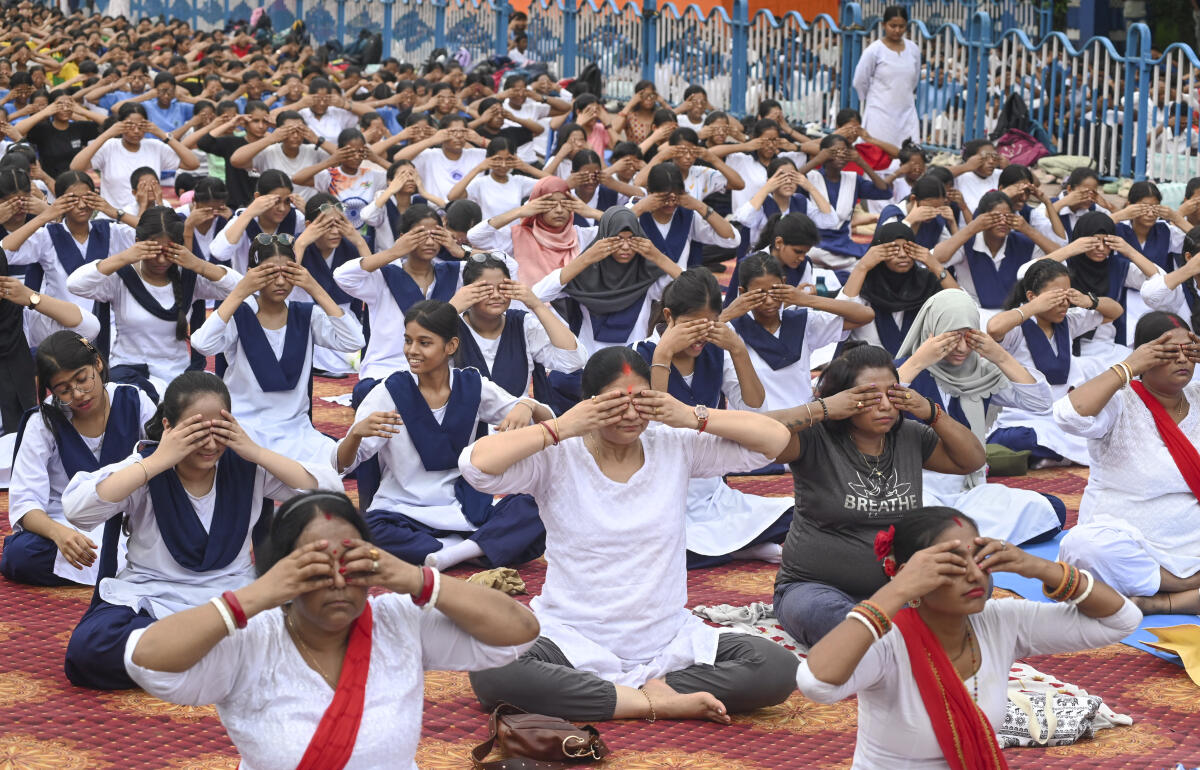 Women, including students, perform yoga on the occasion of the ‘11th International Day of Yoga’, at Esplanade, in Kolkata.