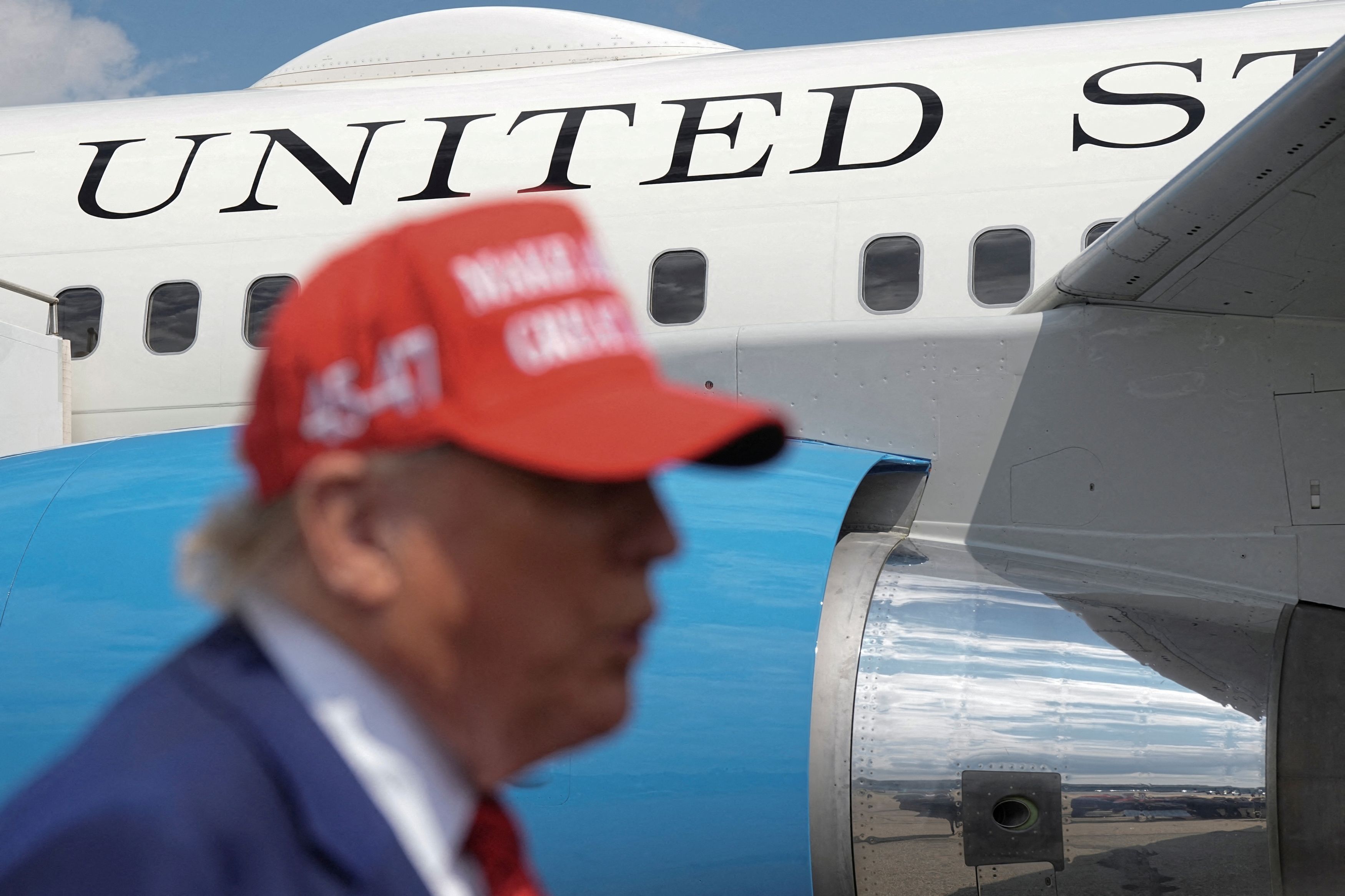 U.S. President Donald Trump talks to reporters as Air Force One is seen in the background upon his arrival at Morristown Municipal Airport in Morristown, New Jersey, U.S., June 20, 2025.