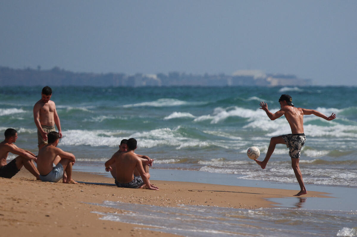 Israelis enjoy the sun by the beach of the Mediterranean, in Haifa