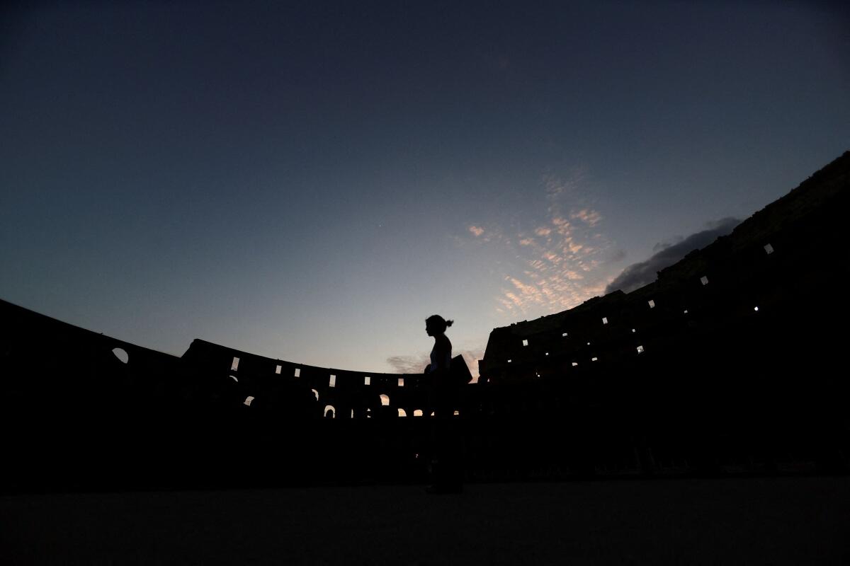 A person strolls inside the Colosseum during a night tour in Rome, Italy