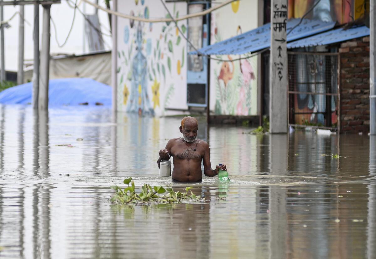 A man wades through an area inundated with water of the swollen Ganga river, in Prayagraj, Uttar Pradesh.