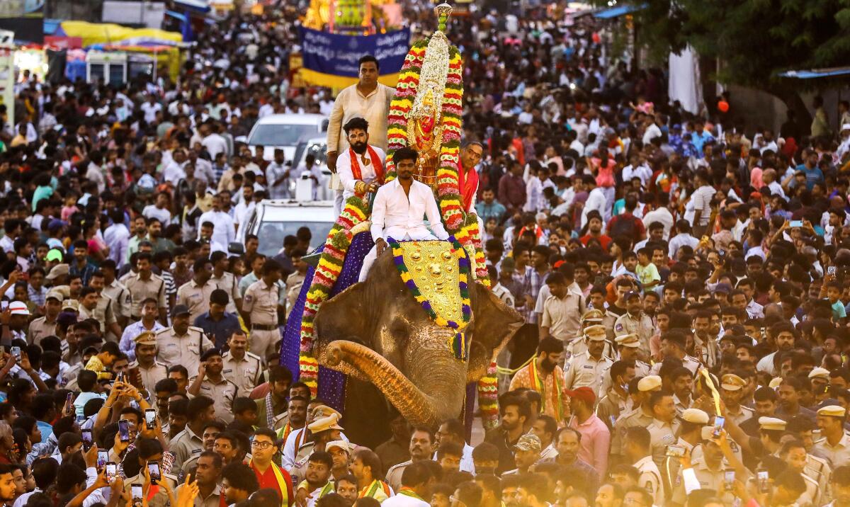 People take part in a procession of the 'ghatam' of goddess Mahakali of Akkanna Madanna temple on a caparisoned elephant as part of the ‘Bonalu’ festival celebration, near Charminar in the Old City of Hyderabad, Telangana.