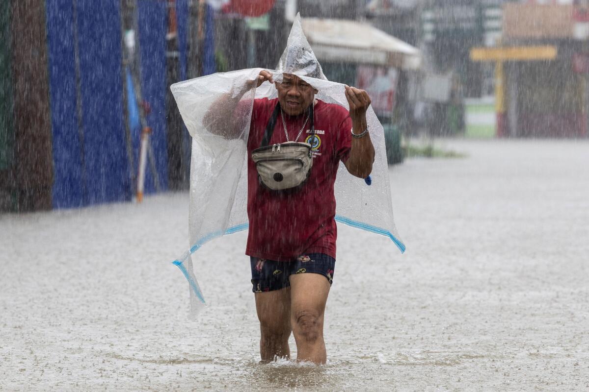 A man wades through a flooded area amid monsoon rains in Cainta, Rizal, Philippines.