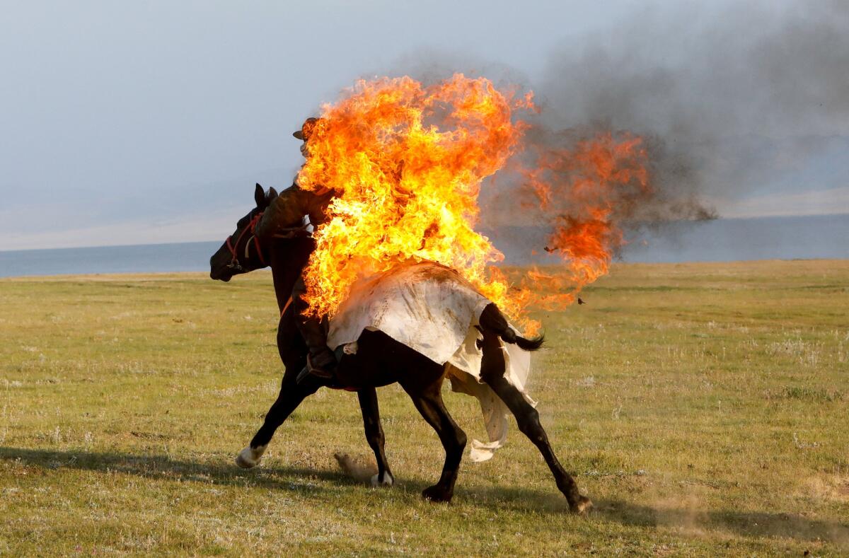 A horseback rider performs a fire stunt during a show organized for the participants of the "Gallops" orienteering and endurance equestrian race, involving international teams of 5 or 6 members, near Lake Song Kol in an alpine valley in the Naryn region, Kyrgyzstan.