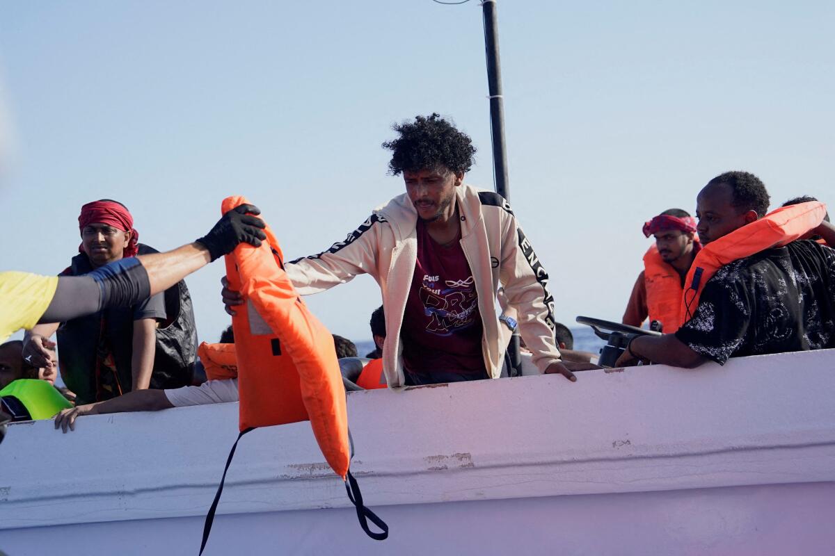 NGO Open Arms rescue boat "Astral" lifeguard Pau Perez, 36, hands out a life jacket to a migrant aboard a fiberglass boat in international waters south of Lampedusa, in the Mediterranean Sea.