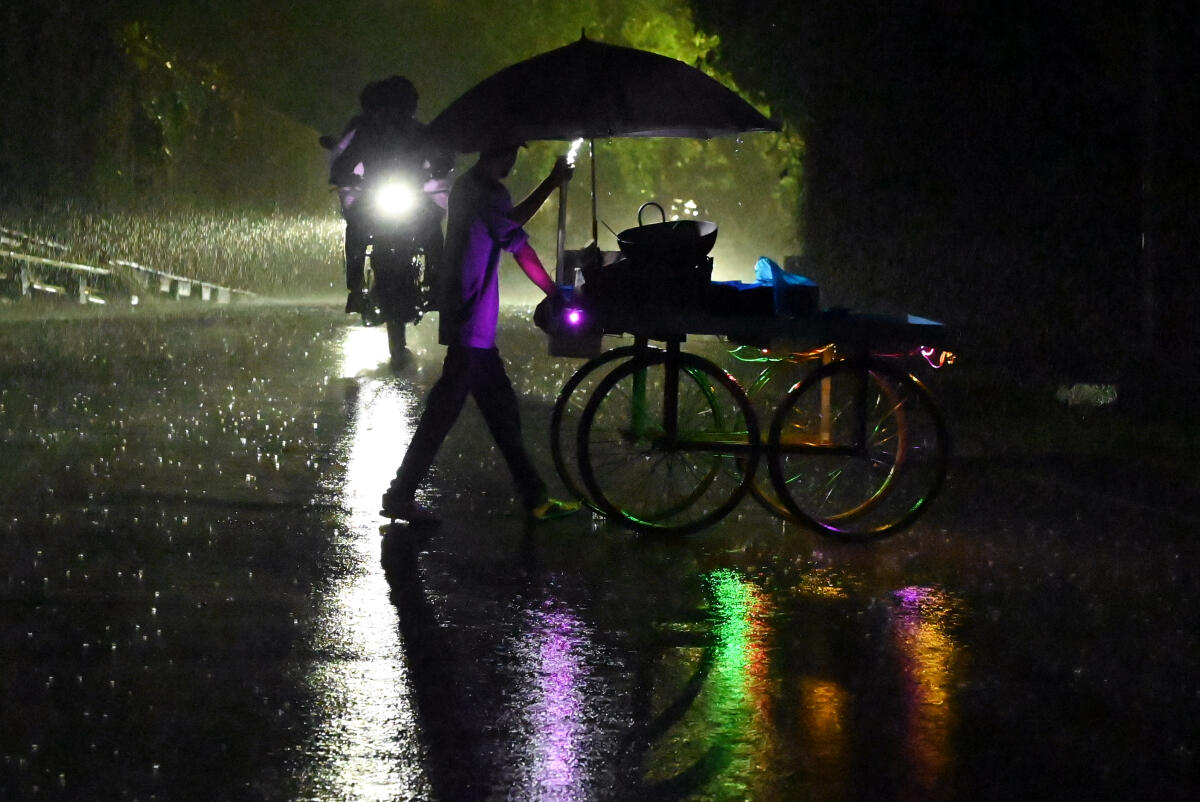 A man pushes his cart amid rainfall, in Thiruvananthapuram, Kerala