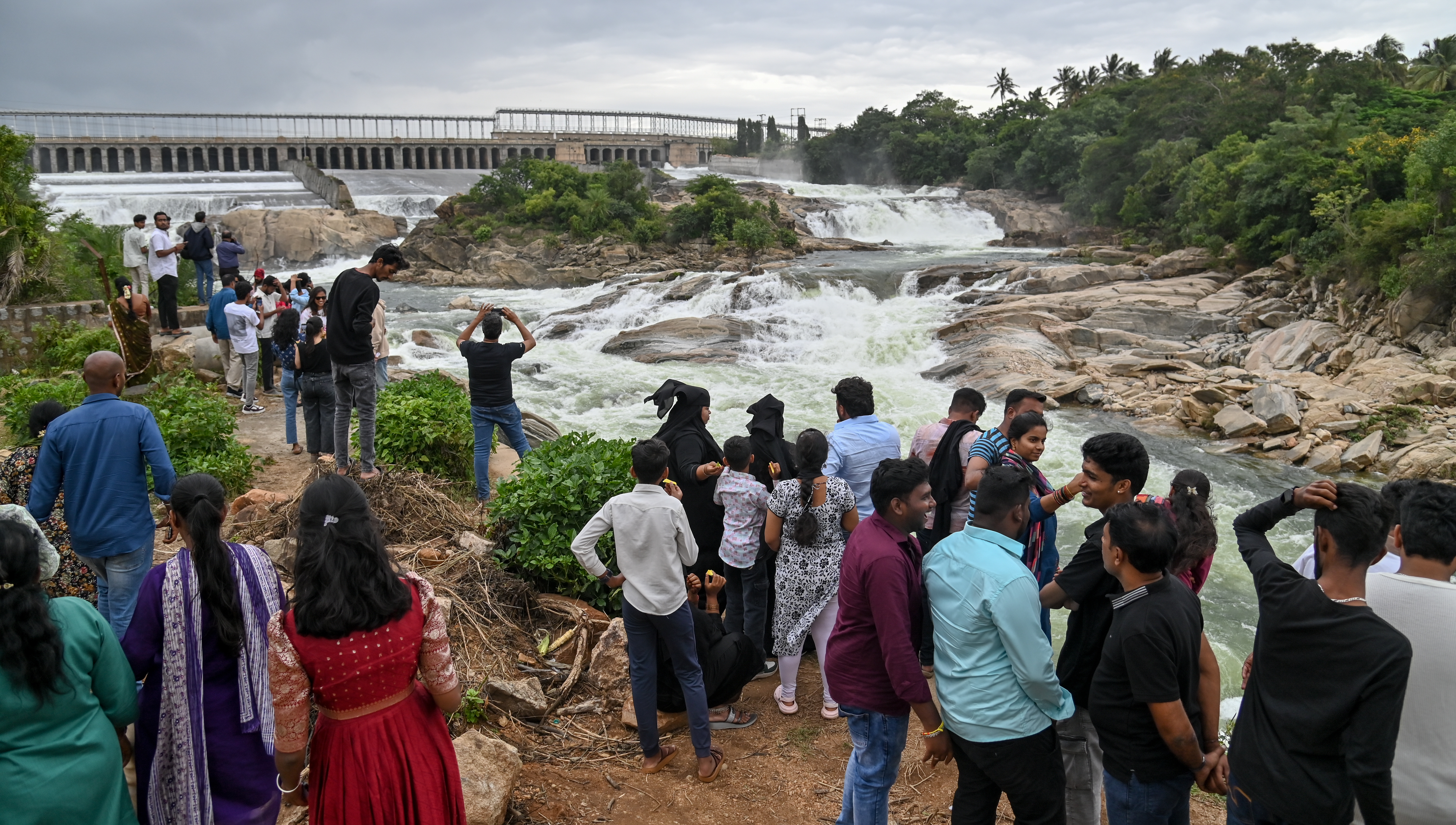 A large number of people throng Krishnaraja Sagar to catch a glimpse of water gushing through crest gates on Sunday. With the dam clocking copious inflows authorities released 56000 cusec downstream.