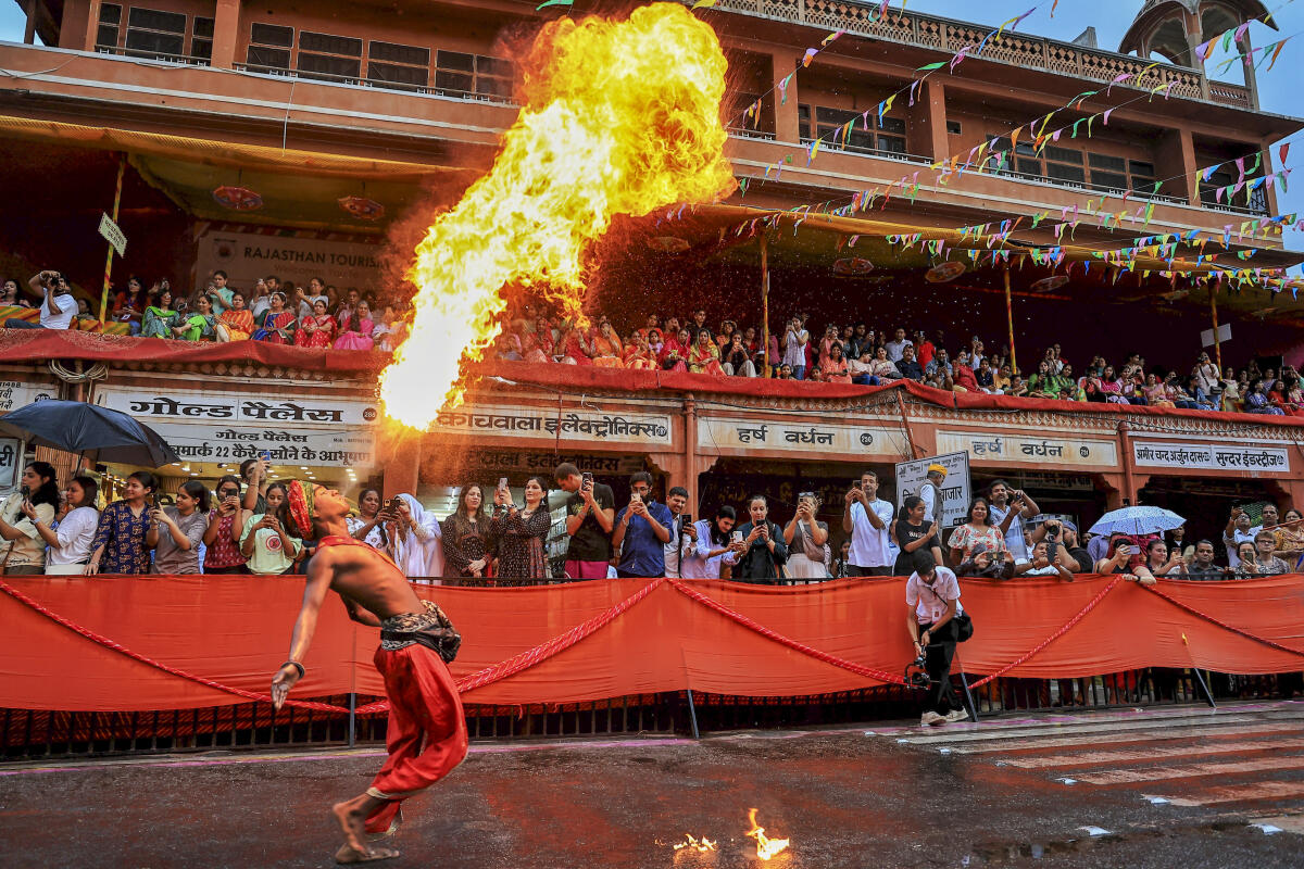 An artist breathes fire during a traditional Teej procession, near Tripolia Gate, in Jaipur