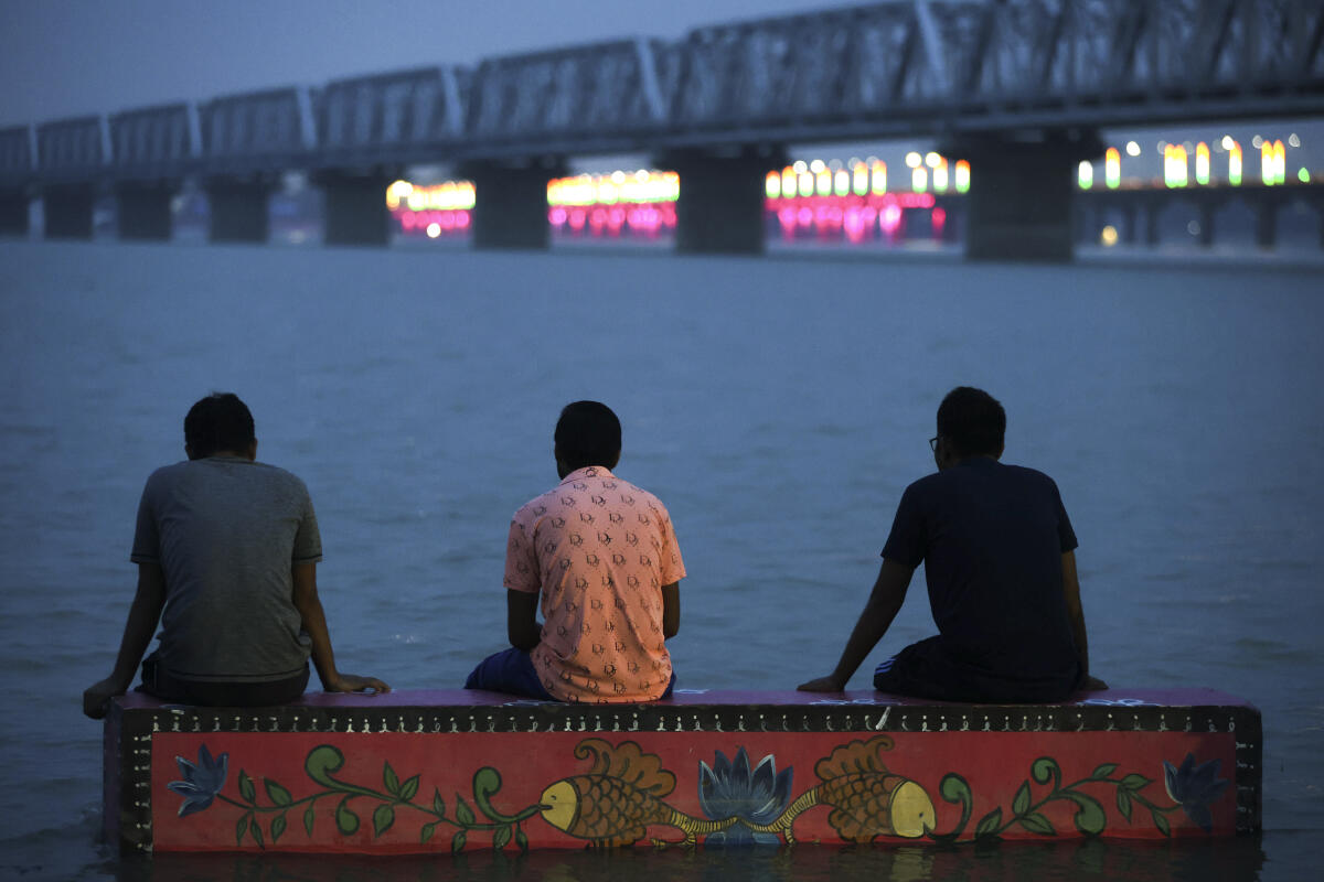 People look at the swollen Ganga river at Dashashwamedh Ghat, in Prayagraj