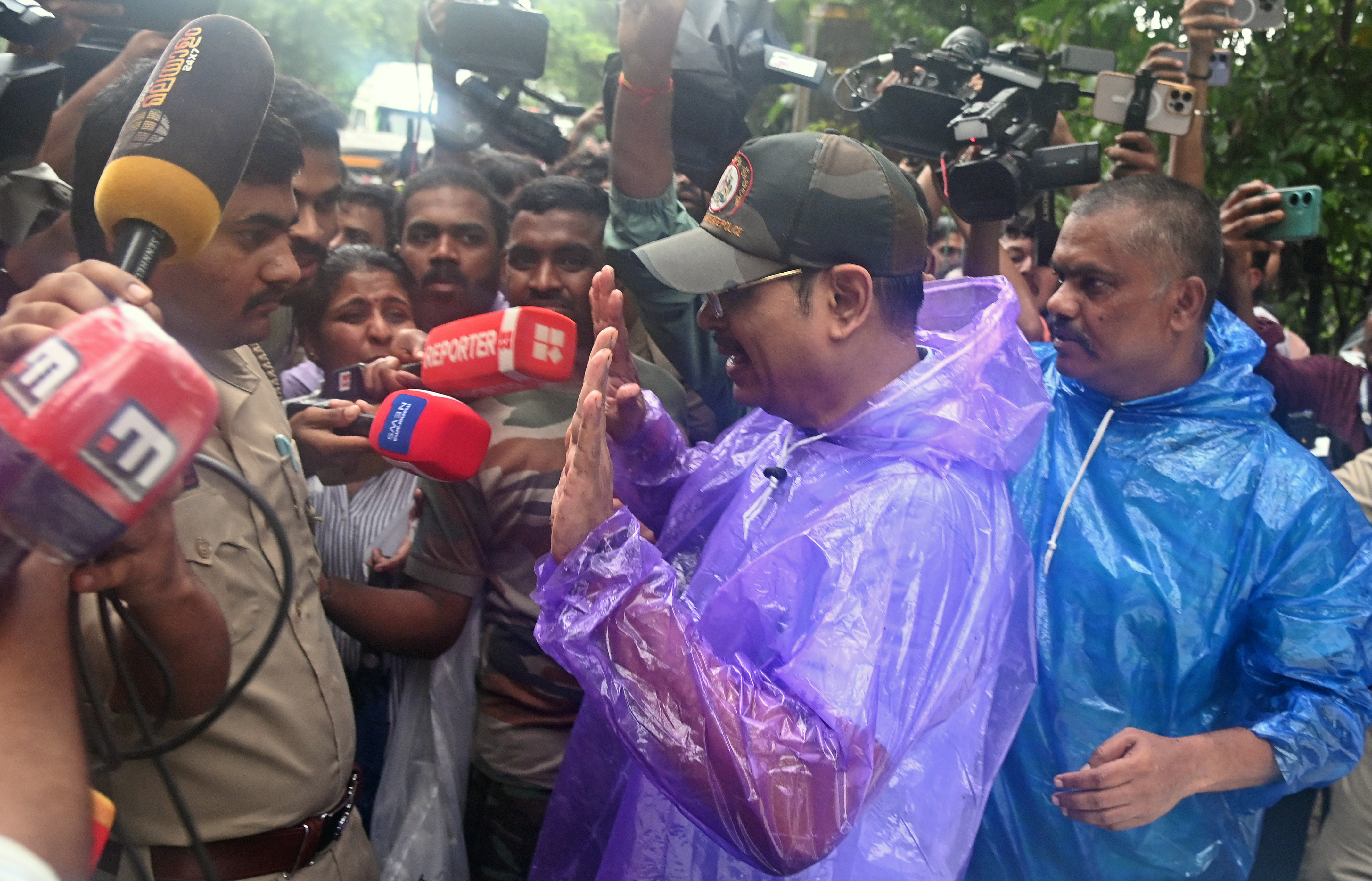 caption: SIT head and Director General of Police (Internal Security Division) Pranav Mohanty who stepped out of the forest after inspecting the exhumation process being mobbed by journalists near the bathing ghat in Dharmasthala on Wednesday. DH photo/Fakruddin H