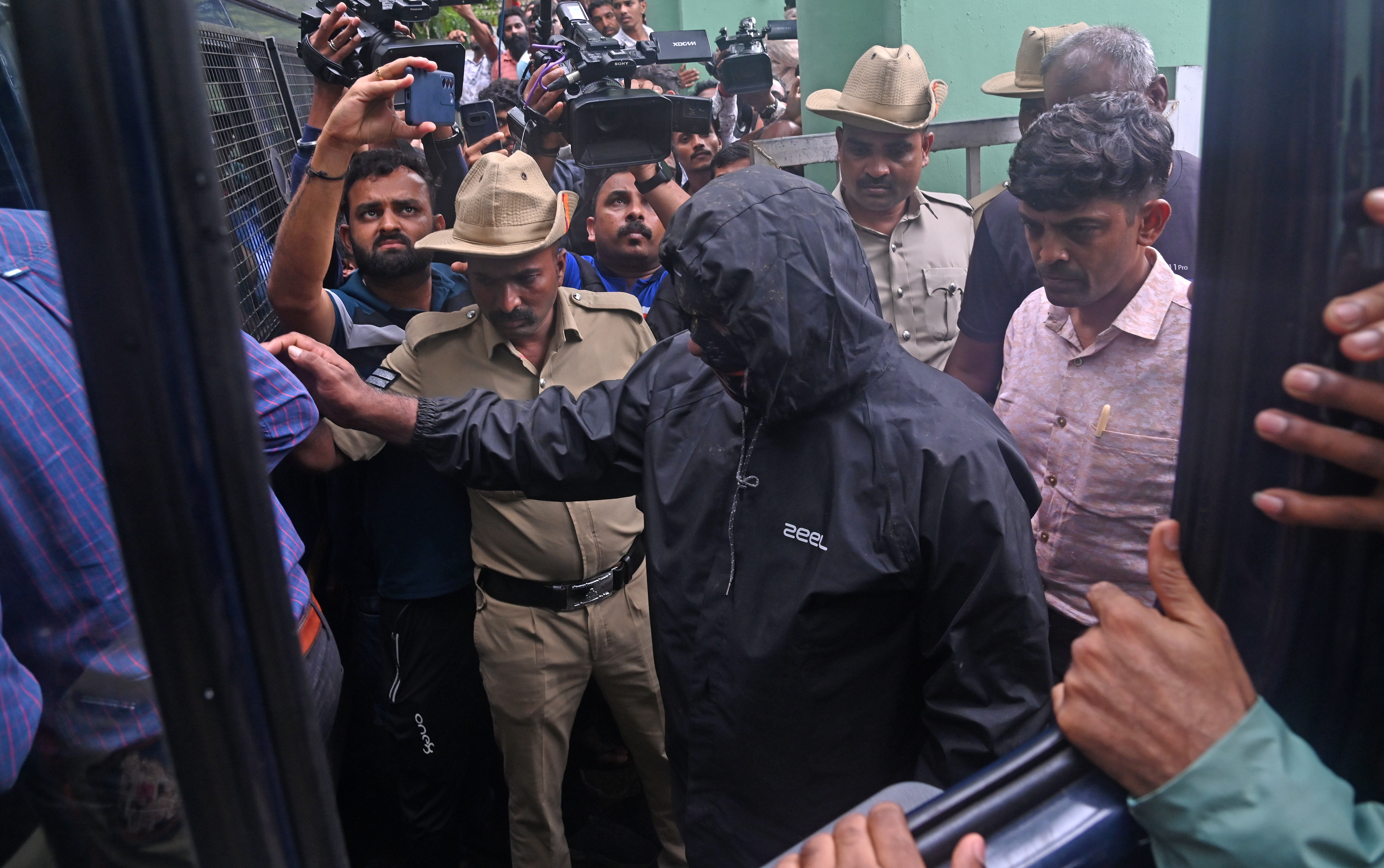 The complainant-witness being escorted to the waiting vehicle after the end of exhumation at five sites near the bathing ghat in Dharmasthala on Wednesday. DH photo/by Fakruddin H