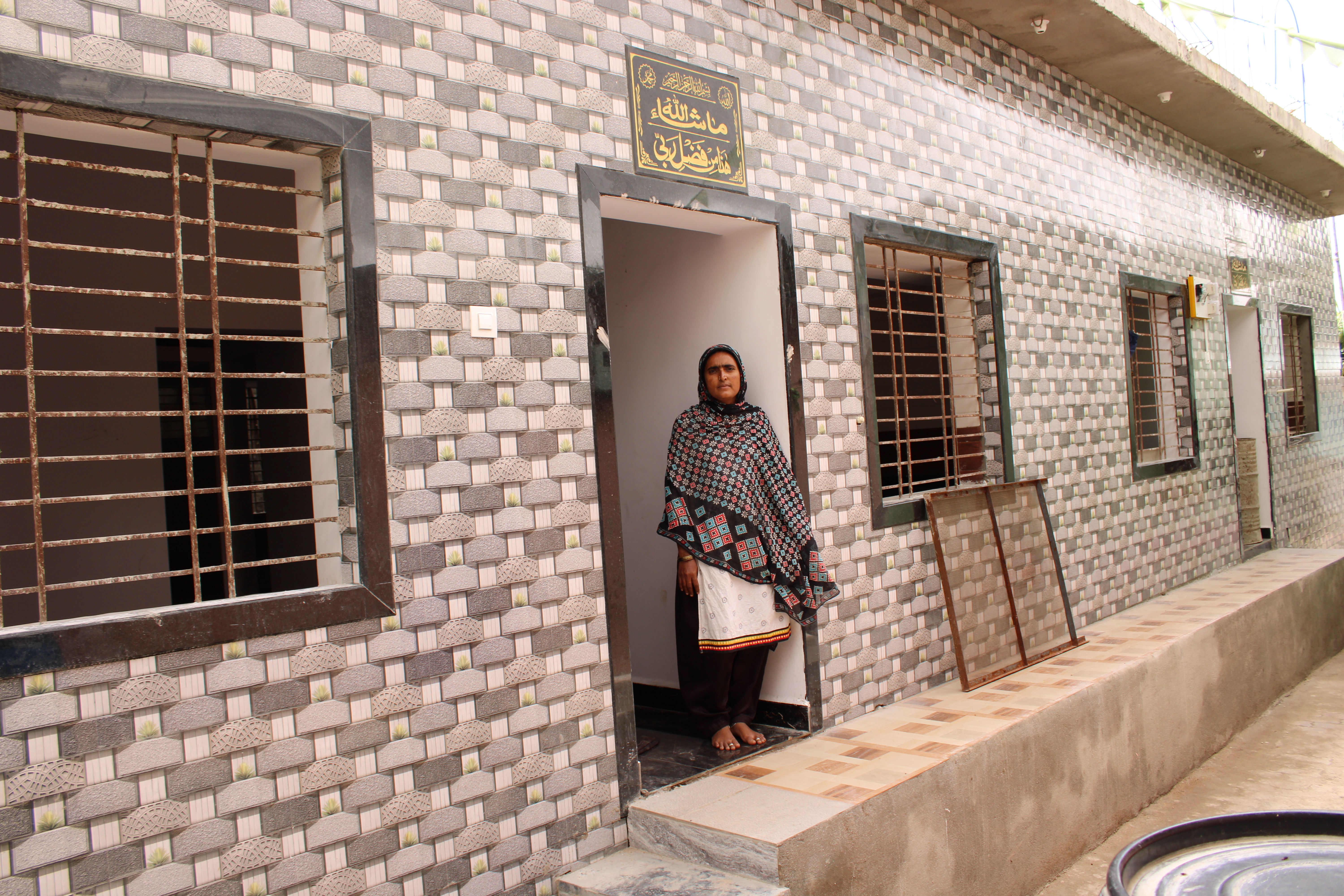 A woman stands in front of her doorless home in Dawal Malik. 