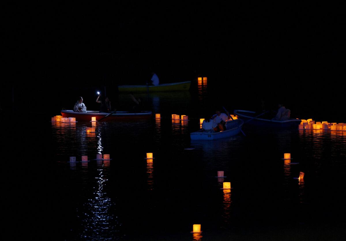 People sail boats around floating lanterns during the Lantern Floating Festival in Tokyo, Japan, July 31, 2025. About a thousand lanterns, inscribed with messages of gratitude, hope, and wishes, are released onto the water during the festival.