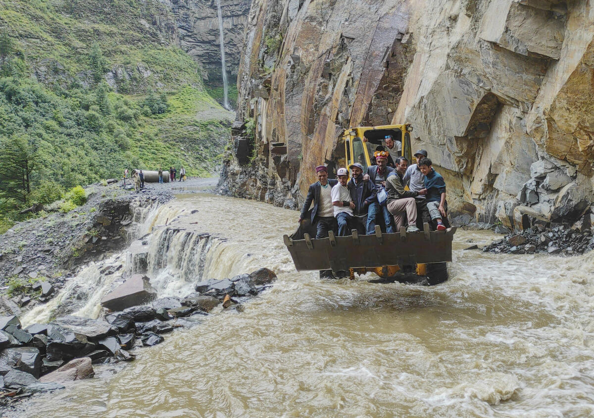 An excavator being used to assist people to cross a stream, in Lahaul and Spiti district of Himachal Pradesh, Friday, Aug. 1, 2025.