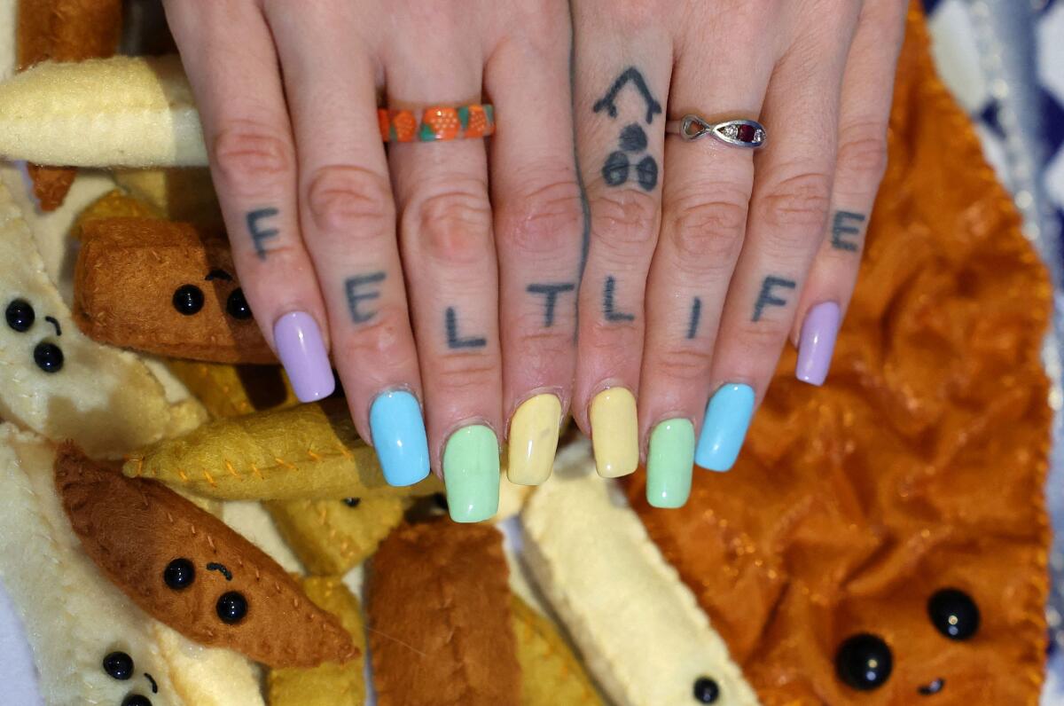 British artist Lucy Sparrow displays tattoos on her hands inside her immersive felt installation, 'The Bourdon Street Chippy', a life-size recreation of a traditional fish-and-chip shop featuring over 65,000 handmade pieces, on its opening day at Lyndsey Ingram Gallery in Mayfair, London, Britain, August 1, 2025.