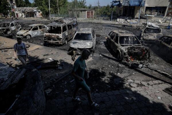 Residents walk past burned cars hit by a Russian drone strike, amid Russia's attack on Ukraine, in the town of Druzhkivka, Donetsk region Ukraine August 2, 2025.