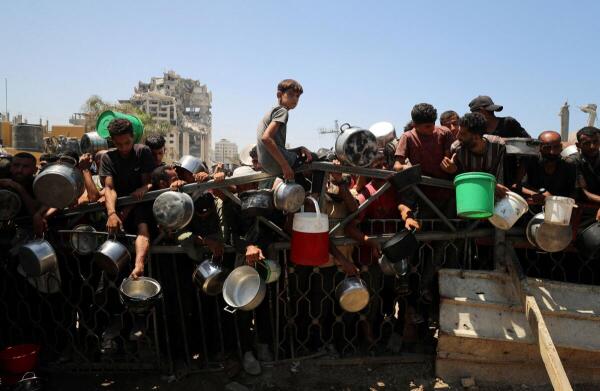 Palestinians wait to receive food from a charity kitchen, amid a hunger crisis, in Gaza City.